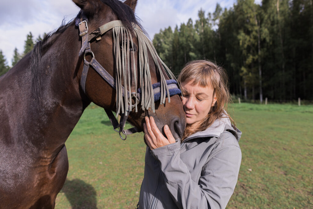 Hevonen on ihmeellinen ja rauhoittava eläin. Kuvassa hevosen turpa vasten ihmisen kasvoja. Kuvassa minä ja Onkku.