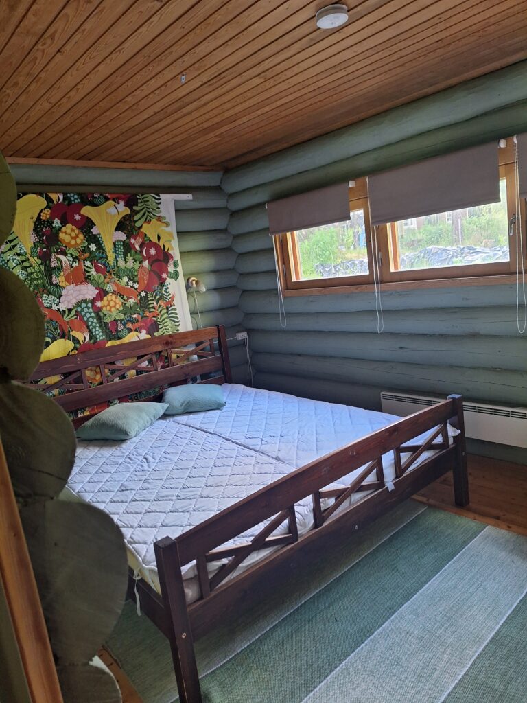 Vihreä makuuhuone ovelta katsottuna. Kuvassa näkyy parisänky, ikkunat ja seinävaate.