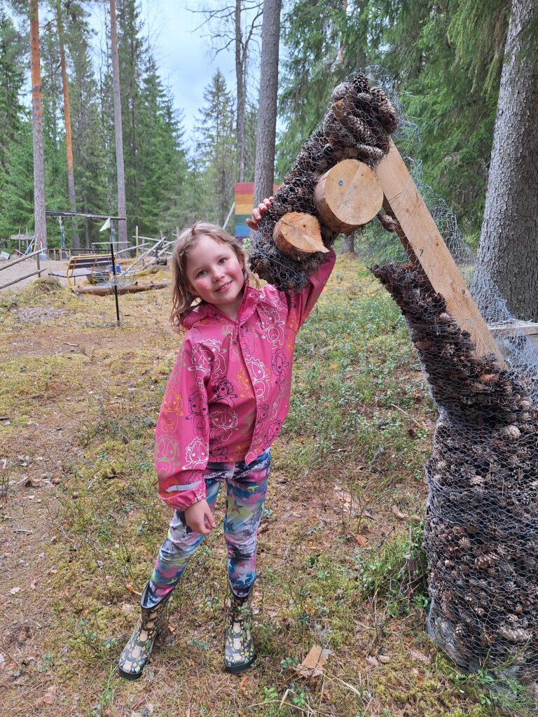 Lammaskahvila - kuvassa huolihevonen eli laudoista ja kanaverkosta rakennettu hevonen, jonka sisällä on käpyjä. Käpyjä voi kerätä kuka vaan omien huoliensa mukaan ja jättää huolensa käpyjen muodossa hevoseen.