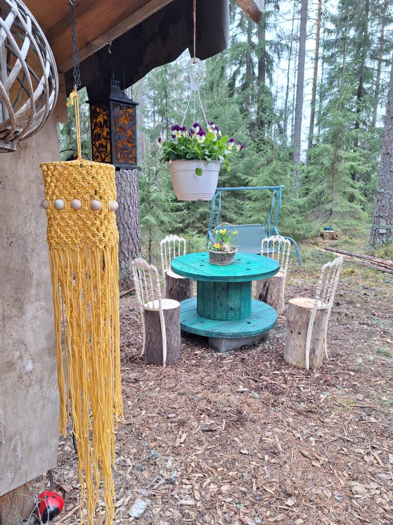 Lammaskahvila - Kuva lammaskahvilan koristeista ja vihreästä pöydästä, jonka ympärillä pölkkytuolit