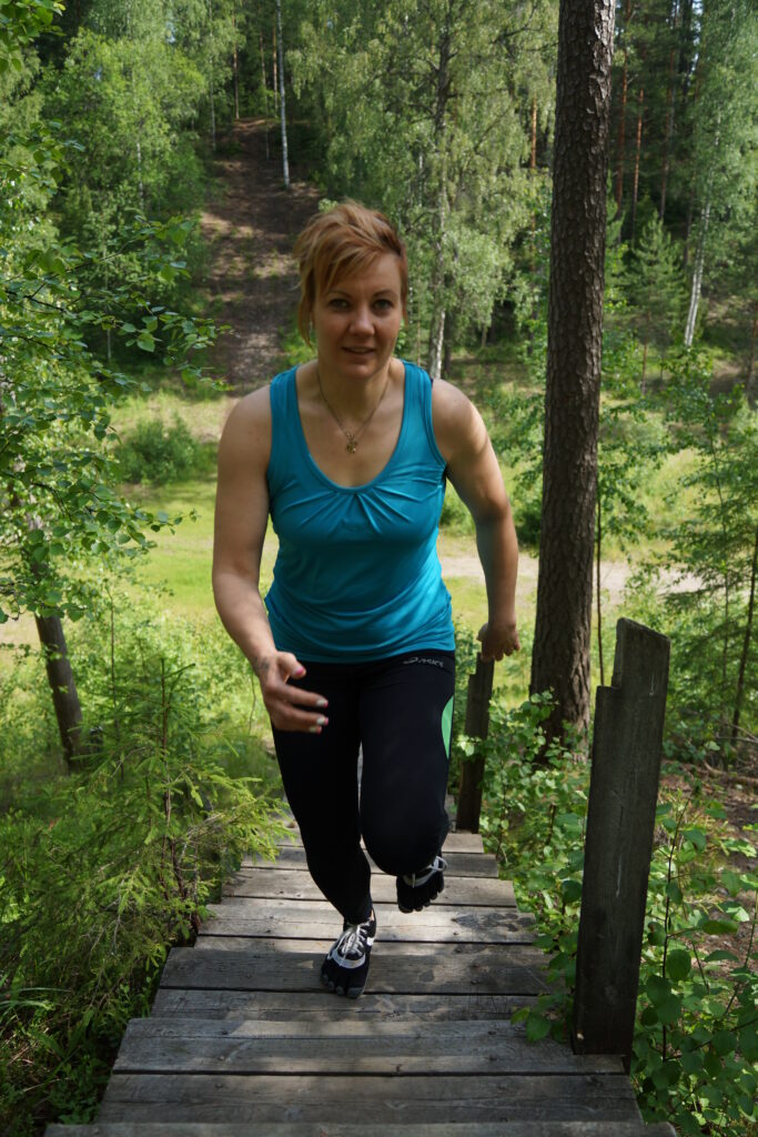 Metsäkuntosali - Luonnossa liikkuminen lisää tasapainoa -Nainen (Anu) juoksee kuntorappusia ylöspäin. Kuva otettu edestäpäin.